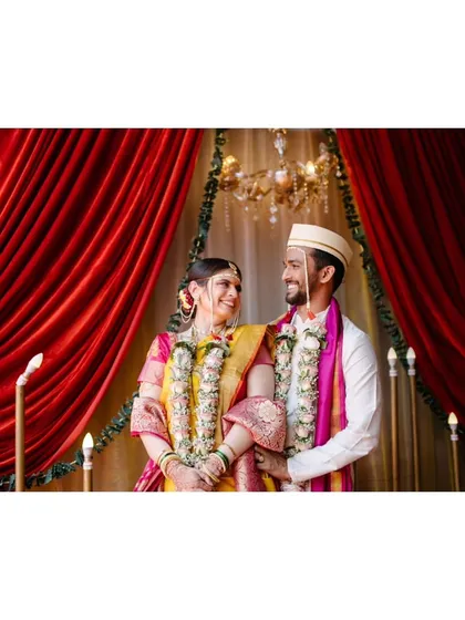 A beautifully framed portrait of the couple against a rich red curtain, symbolizing the love and passion of their union.