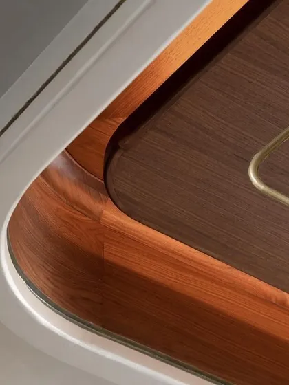 A study in curves. This image captures the elegant, steam-bent wood and metal that form the edge of a custom console. The integrated lighting casts a warm glow, highlighting the seamless joinery and the beauty of the material.