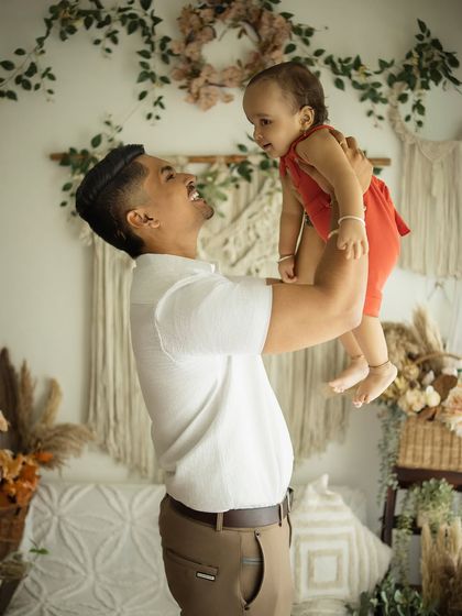 Pure joy in a father-son moment. The dad lifts his son into the air, both of them laughing, creating a dynamic and heartwarming memory during their family lifestyle session.