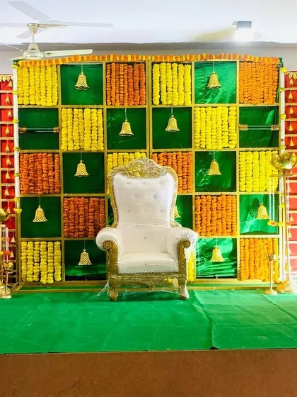 A traditional backdrop for a small ceremony, using a checkerboard pattern of marigolds and hanging bells. The design is simple, auspicious, and perfect for home-based events.