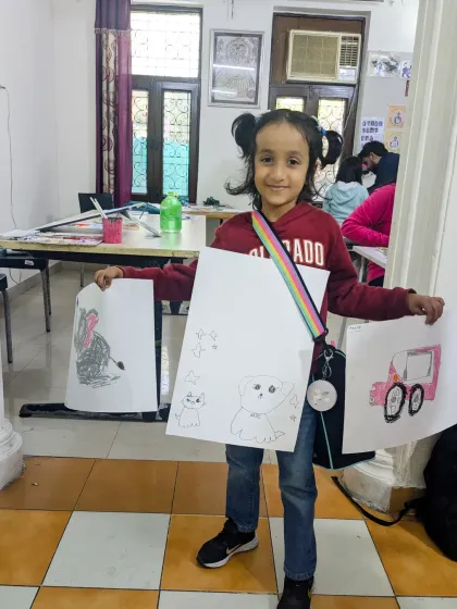 So much creativity in one picture! A young artist shows off her collection of drawings, including cute animals and a cool pink jeep.