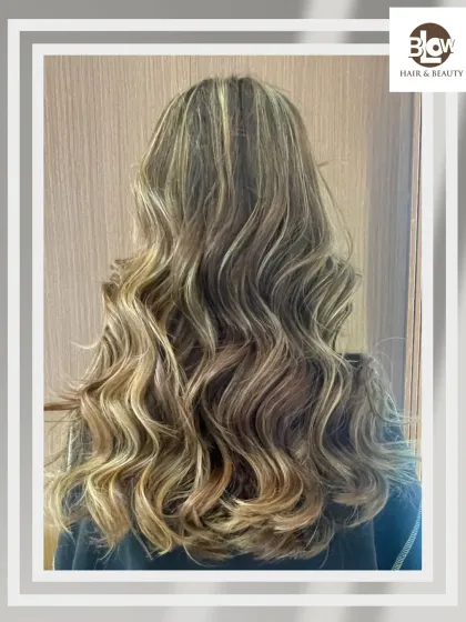 Beautifully styled blonde balayage with soft, flowing waves. This look is all about creating a glamorous yet effortless vibe.