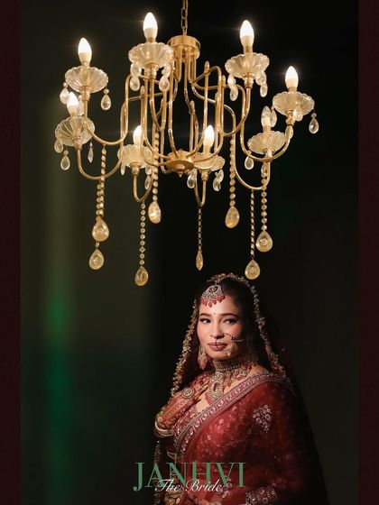 A regal bridal portrait with the bride standing under a grand chandelier. The rich colors and elegant composition create a truly royal image.