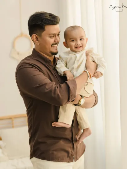 A heartwarming father and son photo. The father holds his laughing baby, capturing a moment of pure joy and connection between them.