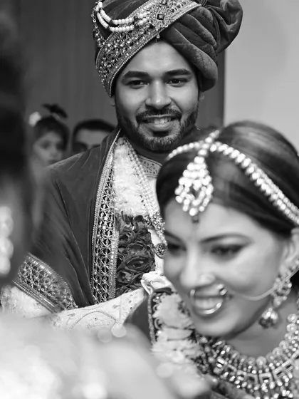 A beautiful black and white candid shot capturing the groom's loving gaze towards his bride during the wedding rituals.
