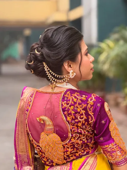 This is a classic Maharashtrian bridal bun, which I have elevated with traditional crescent moon accessories and a delicate chained 'kaan vel'. The intricate twists of the bun are designed to hold securely under a dupatta, making it a perfect choice for a traditional wedding ceremony.