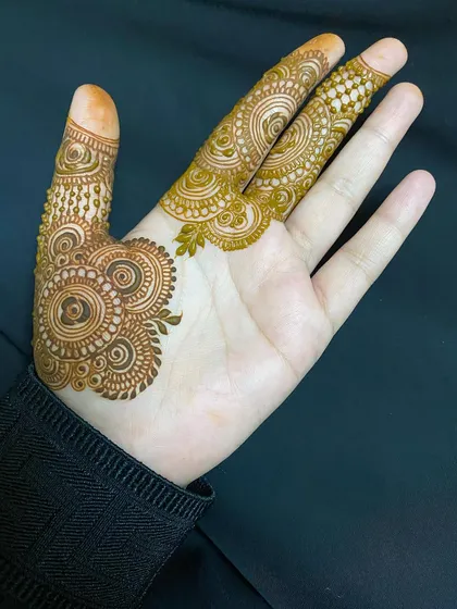 This minimalist design focuses on the palm, with a small circular motif and detailed work on the fingers.