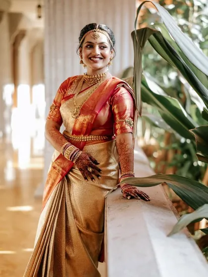 A full-length portrait of the bride in her stunning off-white and red Kanjeevaram saree.