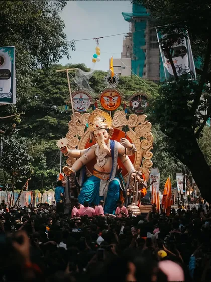 The procession seen from a distance, framed by trees, giving a sense of the journey the idol takes through the neighborhood.