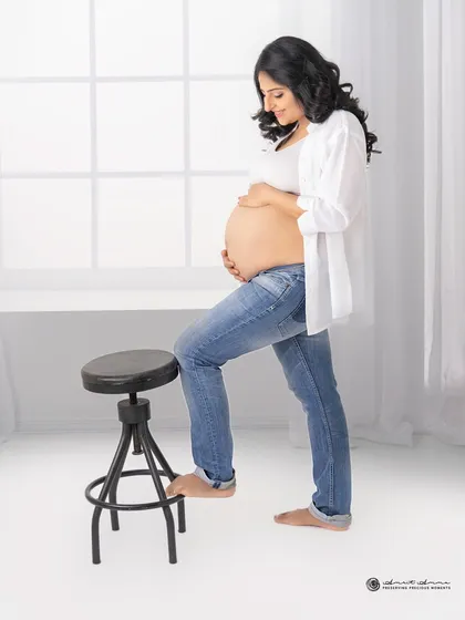 A simple, strong, and beautiful solo portrait. The clean white background and casual styling put all the focus on the beautiful shape of the baby bump.