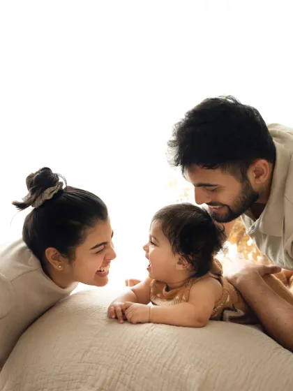 A young family shares a laugh with their baby. The bright, high-key lighting and genuine smiles make this a joyful family portrait.