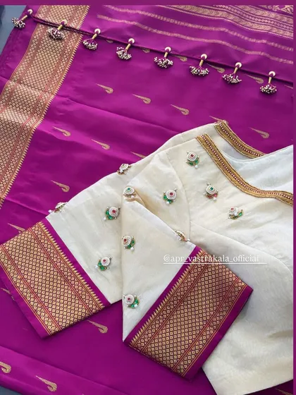 A simple yet elegant white blouse with delicate butti work and a contrasting purple border, paired with a purple silk dupatta.