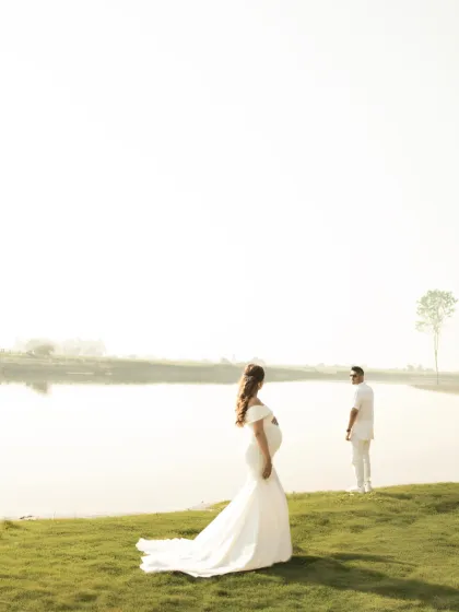 A dreamy, high-key photo of the couple by the lake. The bright, ethereal light and the flowing white gown create a sense of grace and timelessness.