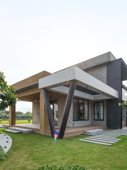 A detail of the outdoor living space at the Sonipat residence. The angled V-shaped columns support the covered porch, adding a sculptural element to the architecture.