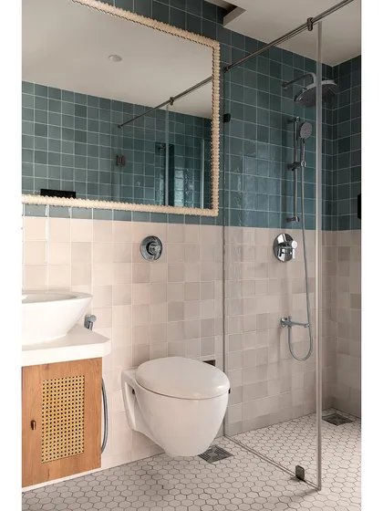 A different angle of the blue and white tiled bathroom, showing the clean lines of the glass shower partition and the simple, modern fixtures. The design is calm, functional, and aesthetically pleasing.