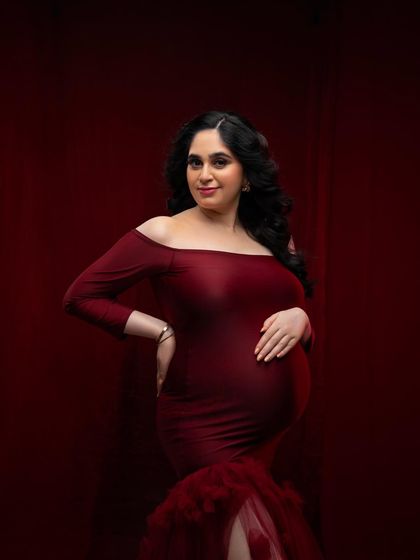 A closer look at the details of this beautiful red gown. The off-the-shoulder neckline and soft fabric beautifully frame the mother's glowing face and baby bump.