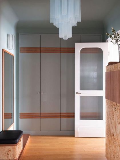 This design showcases an 8-foot-long openable wardrobe with solid color shutters and wood strip inlays. The setup includes a matching dresser and a puffy for a complete and functional entryway or bedroom space.