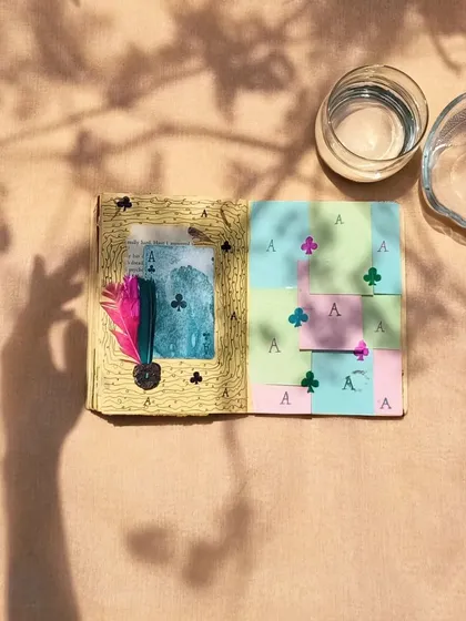 An art journal spread with a playful card theme, photographed with interesting shadows to create a dynamic image.