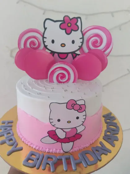 A sweet and simple Hello Kitty cake in her signature pink, decorated with lollipops and macarons for a fun, candy-themed twist.