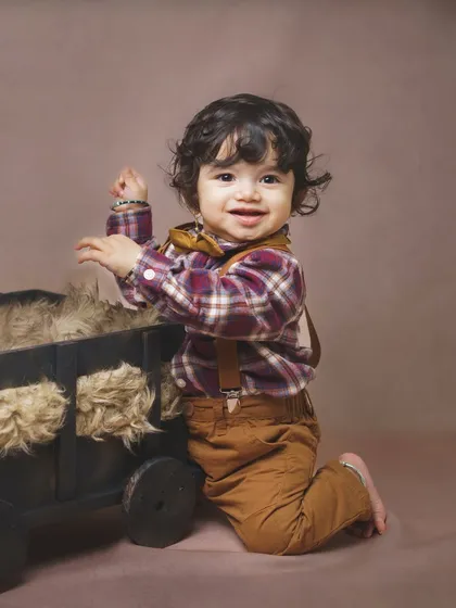 Ready for an adventure! This little boy's happy expression is perfectly captured as he plays with a wooden cart prop during his indoor baby photoshoot.