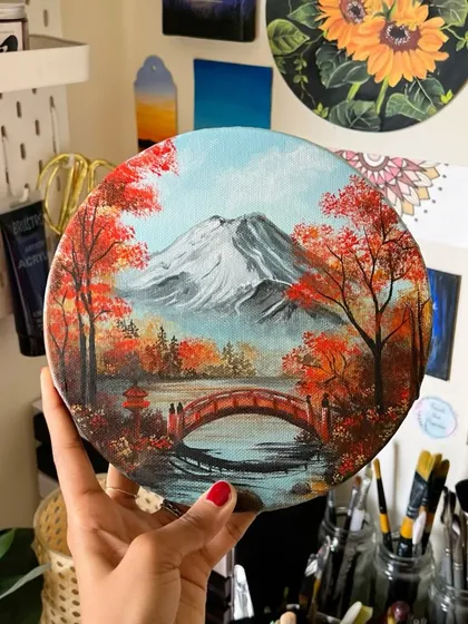 An autumn scene in Japan, featuring a snow-capped Mount Fuji, a traditional red bridge, and vibrant red foliage. This detailed landscape on a round canvas is perfect for anyone who loves Japanese aesthetics.