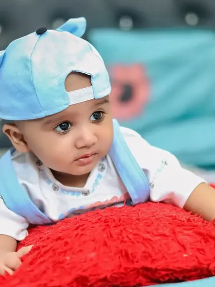 A baby boy looking pensive while resting on a pillow. This portrait showcases his beautiful eyes and sweet expression.