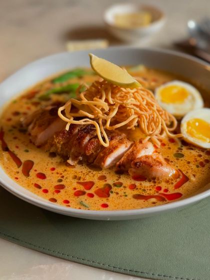 Our classic Khao Suey, a creamy, tangy bowl of homemade noodles, coconut broth, and tender chicken.