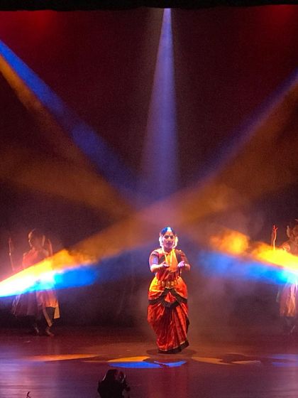 A dramatic moment from 'Akhandalaya', where I stand at the center of intersecting beams of light. The lighting design was crucial in this production to create a sense of cosmic energy and power.