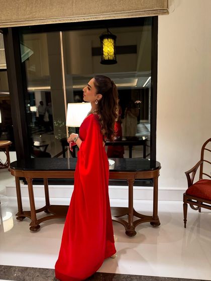 A side profile of the self-designed red saree, showing off the high ponytail and statement necklace that complete this glamorous look for an evening function.
