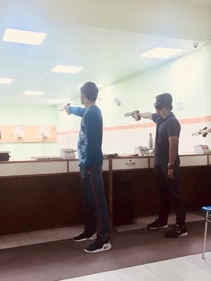 A mixed group of kids and adults practicing their pistol aim together.