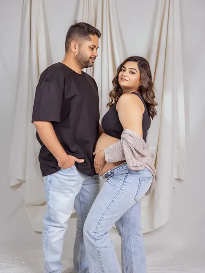 A playful and confident pose that shows the mom-to-be's beautiful bump and the couple's relaxed style.