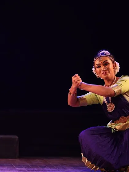 A dancer in a graceful kneeling pose, her expression full of devotion, captured during the Sadhana Classical Dance Festival.