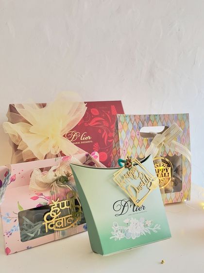A variety of our beautifully designed Diwali gift boxes. We offer multiple packaging styles, from pillow boxes to handled bags, all featuring festive colors and elegant "Happy Diwali" tags.