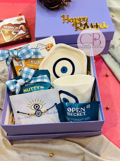 We are crushing on these evil eye themed Rakshabandhan hampers. The beautiful lavender box contains an evil eye mug and trinket tray, healthy snacks from Open Secret, and a matching rakhi.
