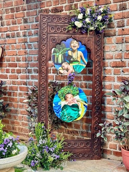 A creative photo display using a traditional carved wooden frame to showcase pictures of the baby. This personal touch was placed within the event space for guests to admire.