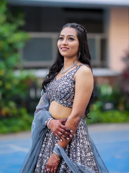 A perfect glam transformation for a sangeet night. The makeup features a soft smokey eye and glowing skin, paired with a half-up hairstyle.