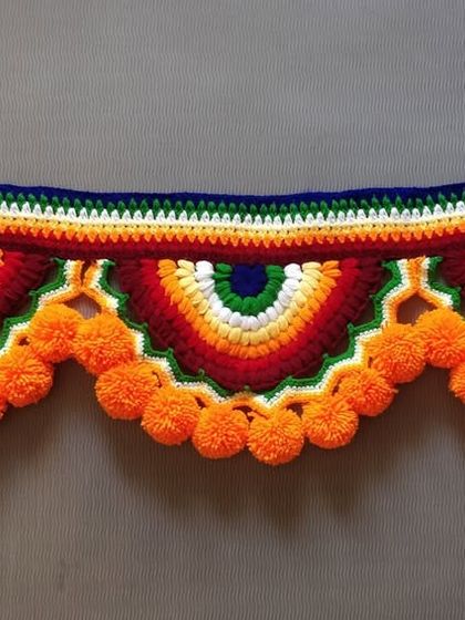 This rainbow-themed toran with orange pom-poms is a very popular design, loved for its bright and cheerful colors.