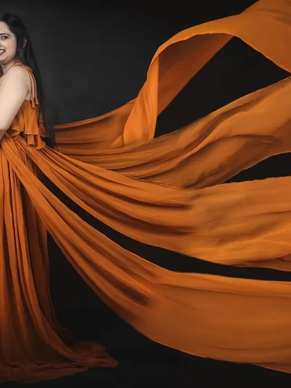 This studio shot showcases the incredible spread of our mustard four-trail gown against a black background, highlighting the color and dramatic flow of the fabric.