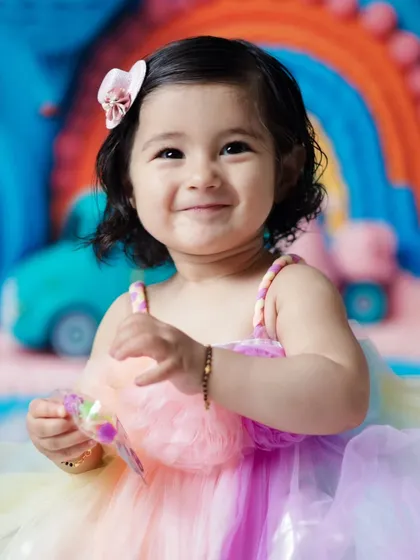 A close-up of this happy baby girl with her colorful rainbow-themed birthday setup. Her genuine smile is what makes these photos so special.