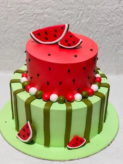 A refreshing watermelon-themed cake. The two-tiered design mimics the look of a real watermelon, inside and out, perfect for a summer party.