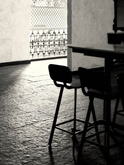 The silhouette of bar stools against the light from an open doorway, highlighting the texture of the stone floor.