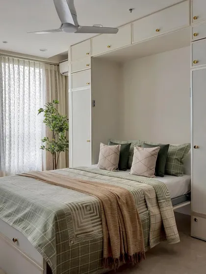This space-saving Murphy bed is surrounded by clean, white cabinetry. The texture comes from the green and beige plaid bedding and the soft, knitted throw, which add warmth and coziness.