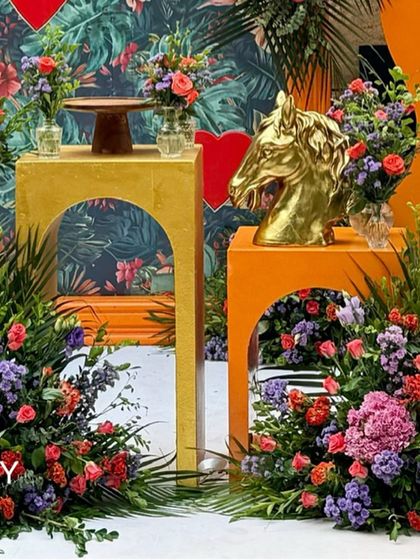 A close-up of the decor pedestals with a golden horse head statue and floral arrangements.