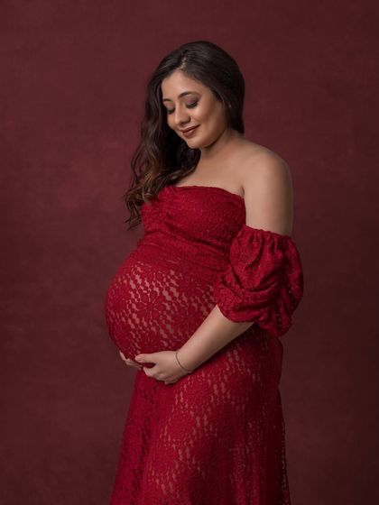 A solo portrait in a gorgeous red lace gown against a deep red backdrop, creating a rich, monochromatic look.
