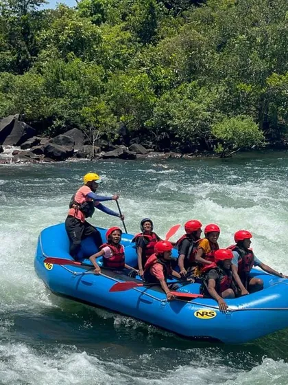 An instructor at the helm guides a raft of young adventurers through the white-water course in Dandeli, ensuring a safe and educational experience.