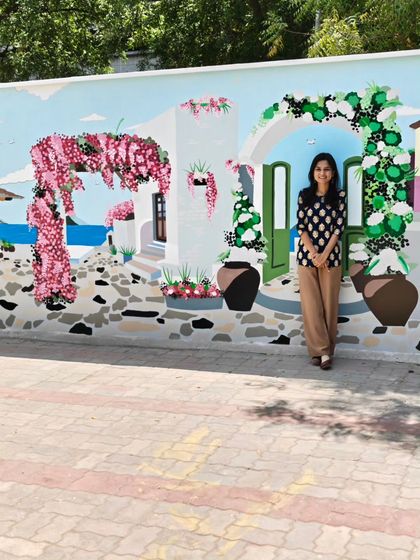 Me posing at a different section of the restaurant mural, in front of a painted archway with white flowers.