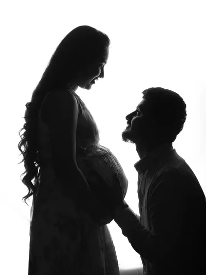 A beautiful silhouette of a husband adoring his wife and their unborn child. The high-key lighting creates a dreamy and angelic feel.