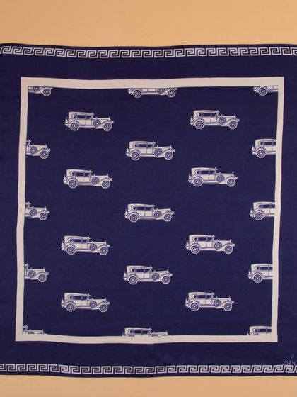 A navy blue pocket square with a vintage car print, shot flat to display the entire design.