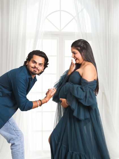 A fun and candid moment from a studio session. The couple shares a playful interaction, showing that maternity photoshoots can be full of laughter and genuine emotion.