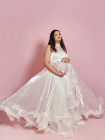 A full-length shot of the Paradise gown against a pink backdrop. The shimmering organza fabric catches the light beautifully, creating a magical glow.